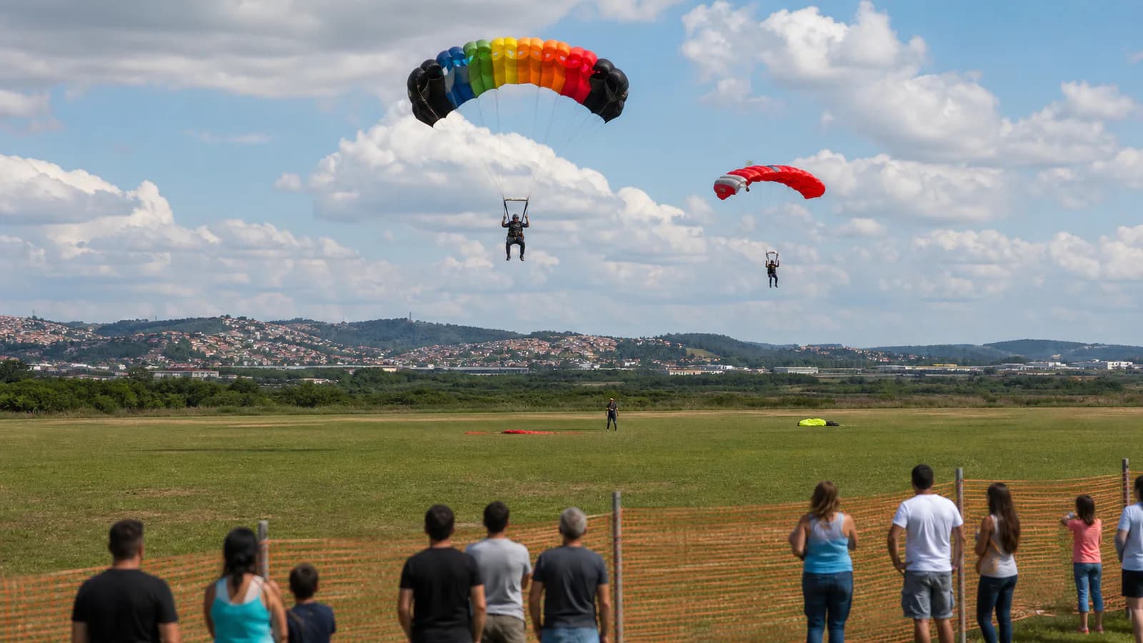 Paraquedistas pousando em área segura diante de visitantes, em imagem editorial conceitual